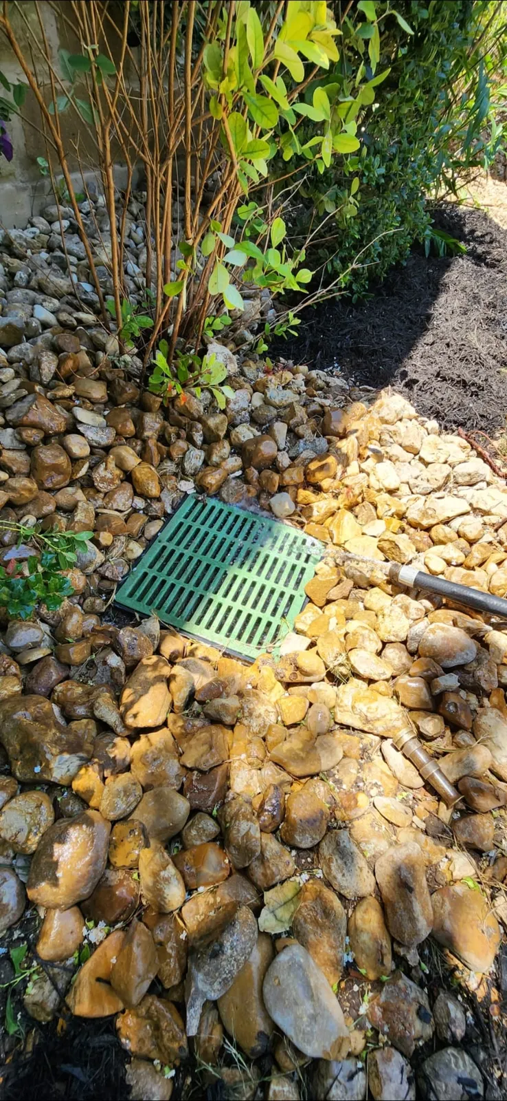 Landscape drainage inlet set in decorative rock