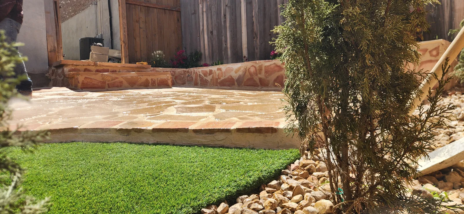 Finished stone terrace connected to a green residential lawn